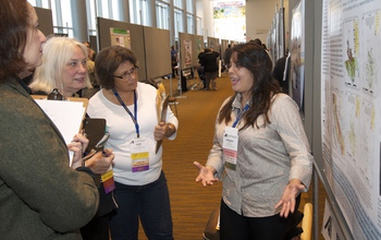 Student standing at poster and talking to 3 other people